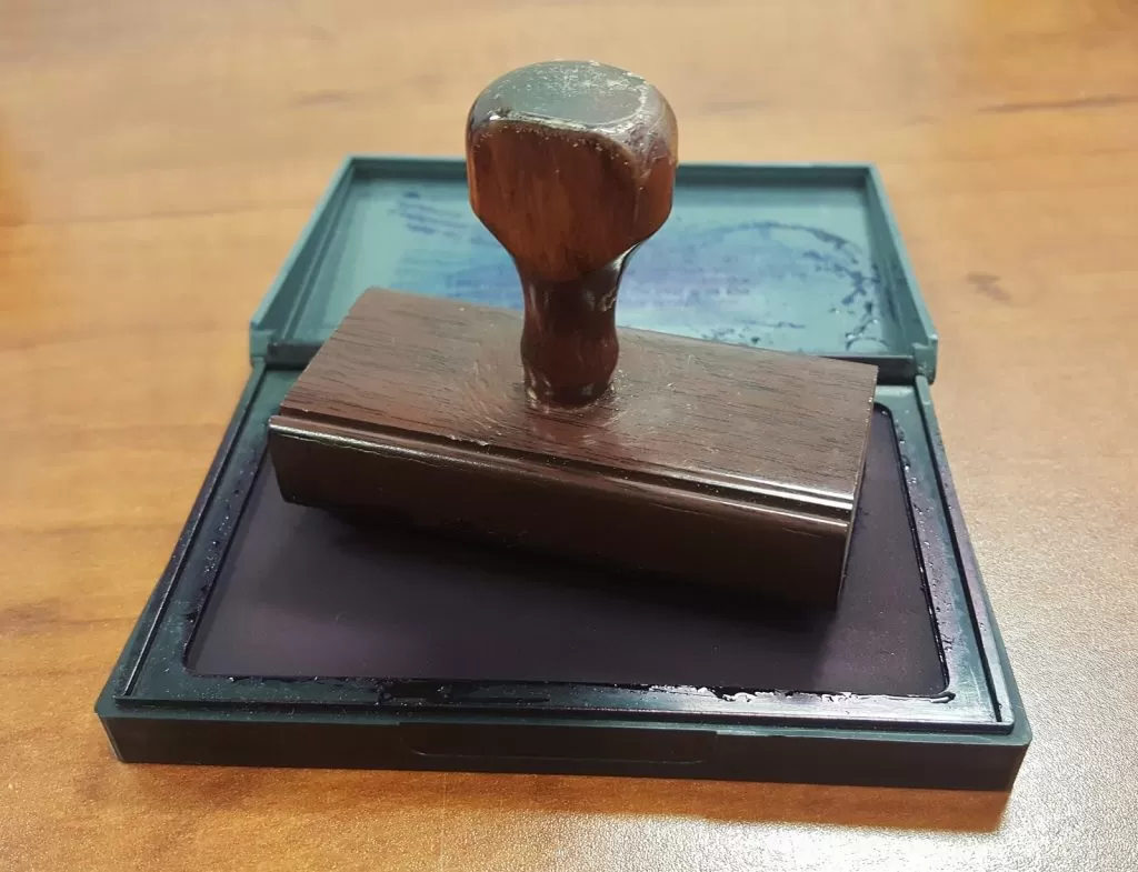 A wooden rubber stamp resting on an open ink pad