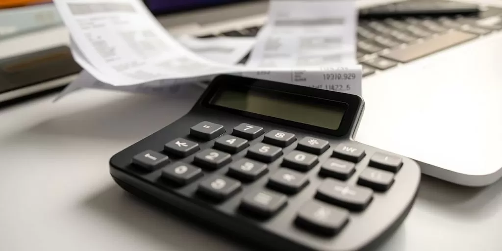 Calculator and receipts on a desk for budgeting.